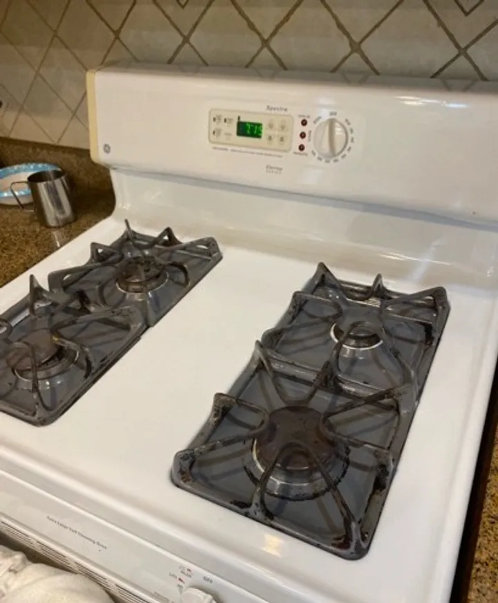 White enamel four-burner gas range with clean grates and control panel